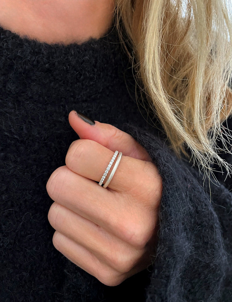 Diamantring och silverring i en ring stack som bärs på pekfingret