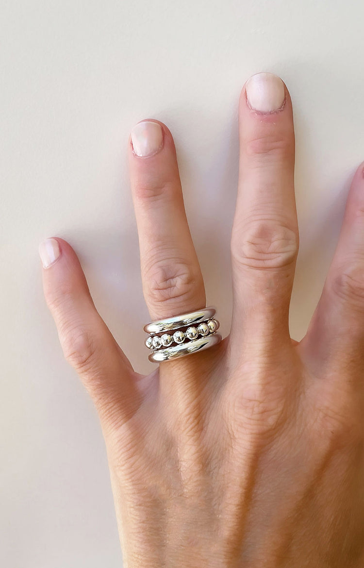tre tjocka silverringar i kombination. två släta ringar och en ring med kulor i mitten.