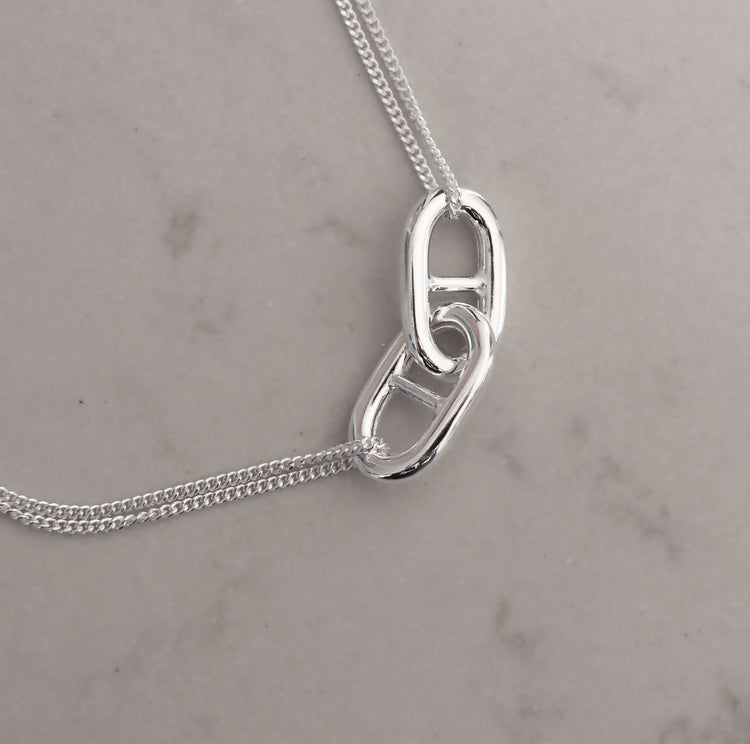 Närbild på två silverlänkar med stavar i mitten.