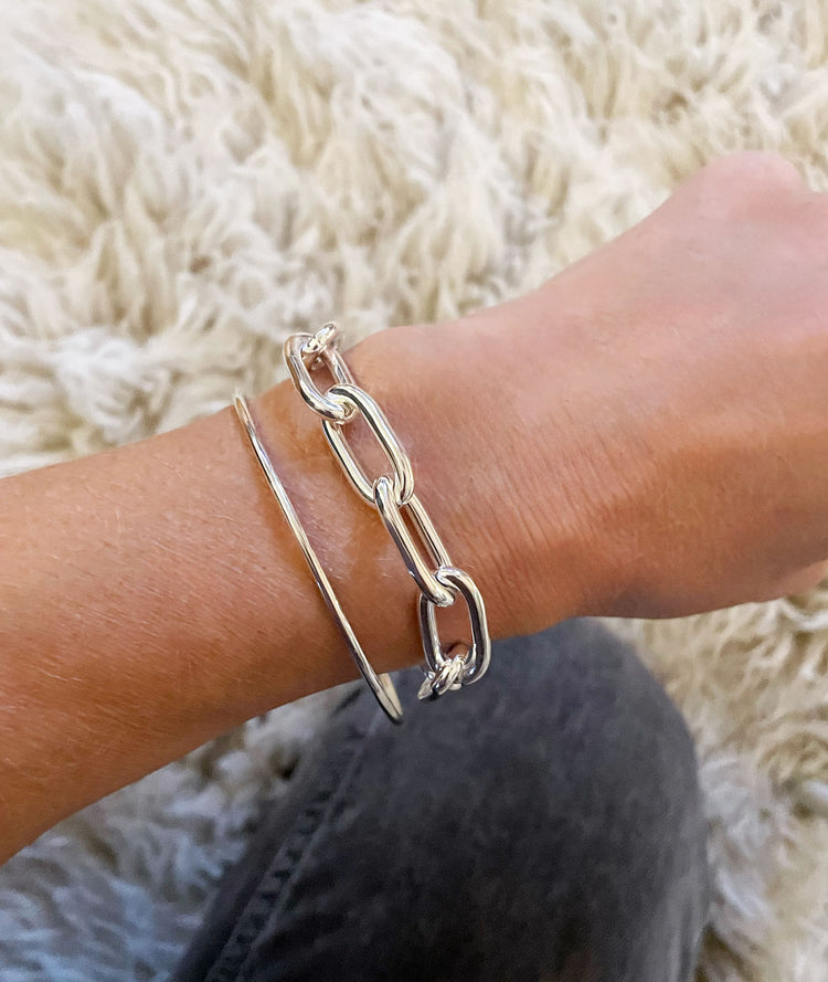 Tjej som bär ett silverarmband med stor kedja som har ovala länkar.