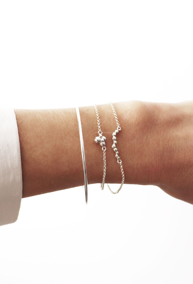 Tjej som bär en kombination av flera armband med kedjor och stelt armband.