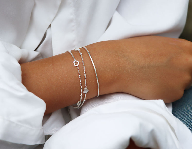 Tjej som bär ett silverarmband med hjärtan.