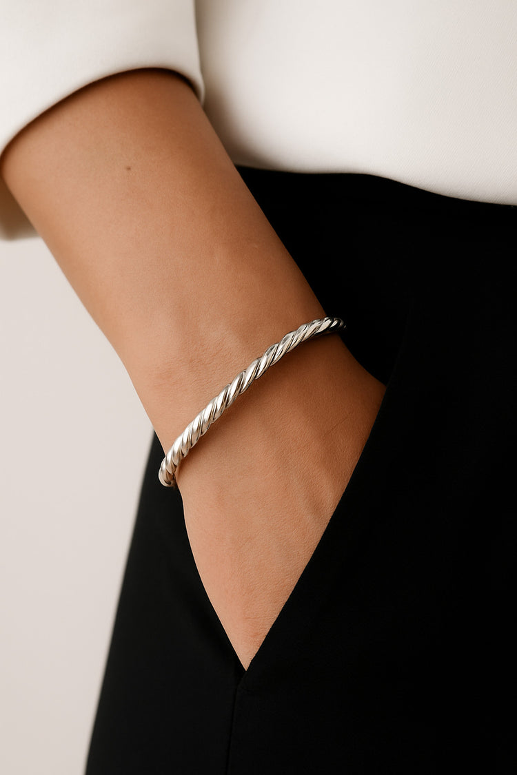 Kvinna som bär ett stelt silverarmband som är tvinnat.