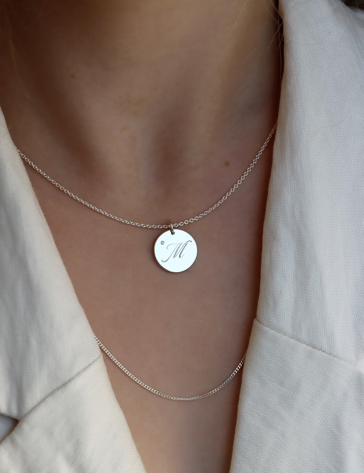 Tjej som bär ett bokstavshalsband med berlock i silver med bokstav + diamant.