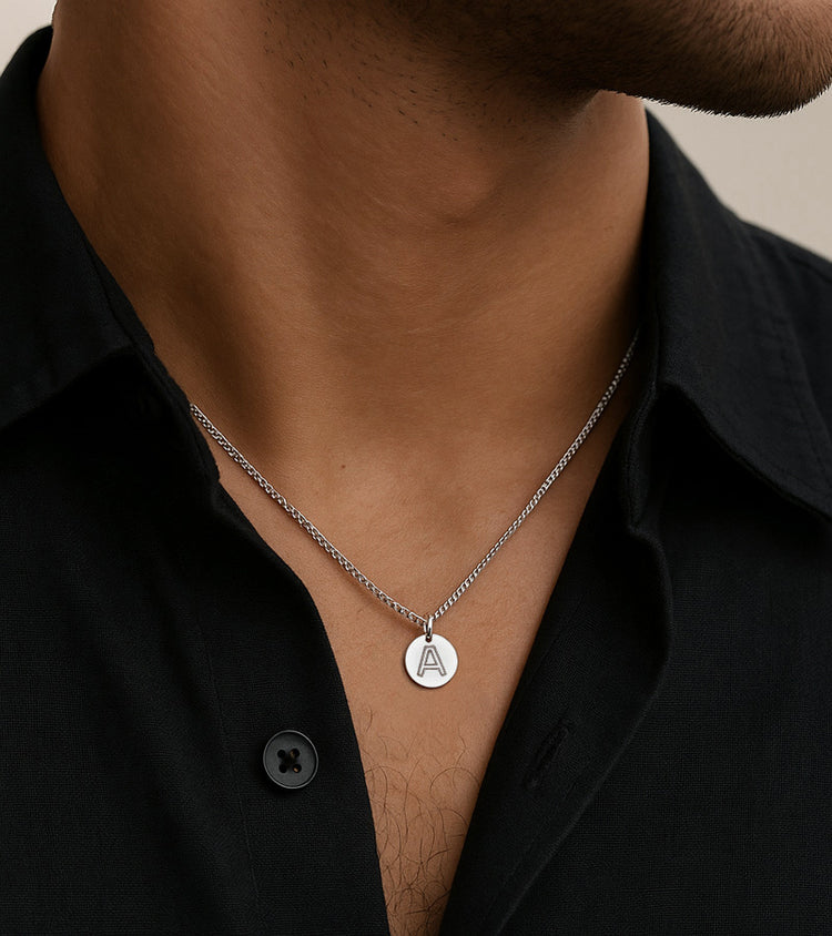 Kille som bär ett halsband med bokstavsberlock i kedja.