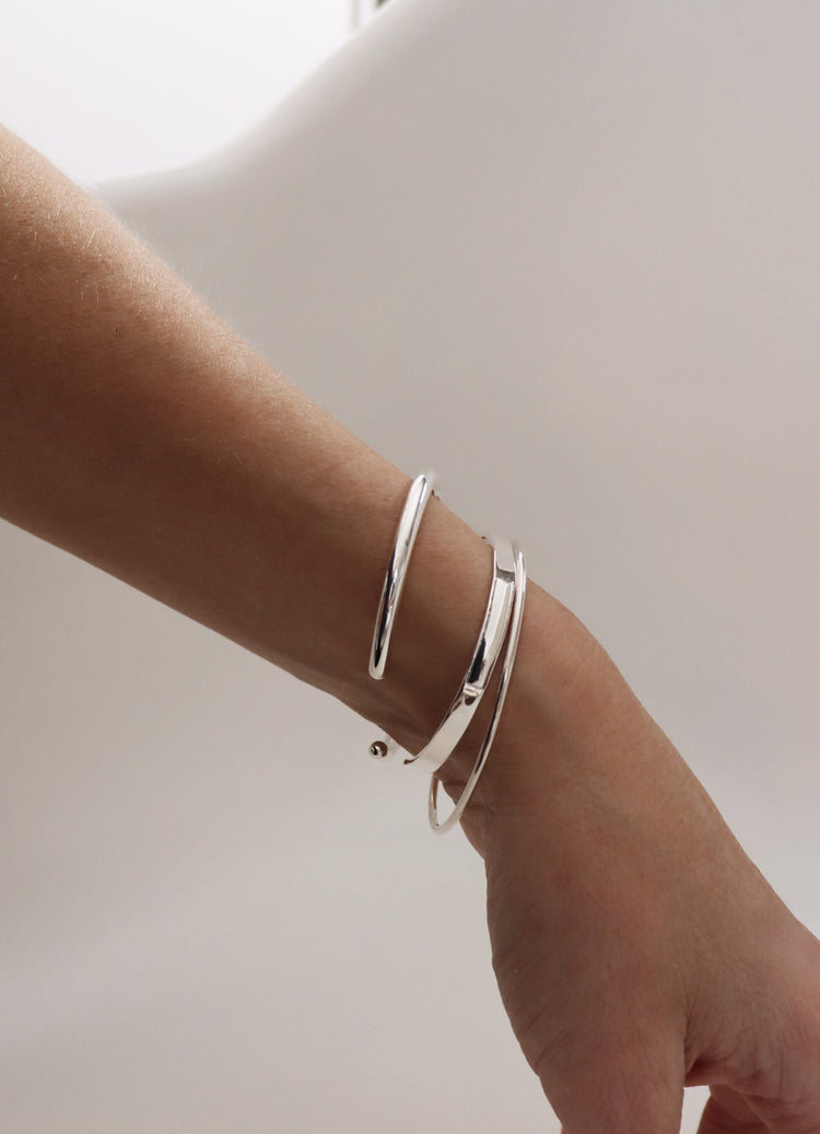 Tre stela silverarmband i kombination på en arm.