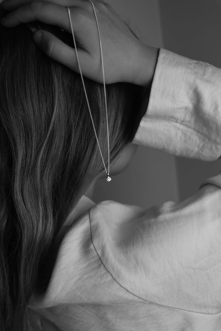 En tjej som håller ett diamanthalsband i handen med en liten gnistrande diamant.