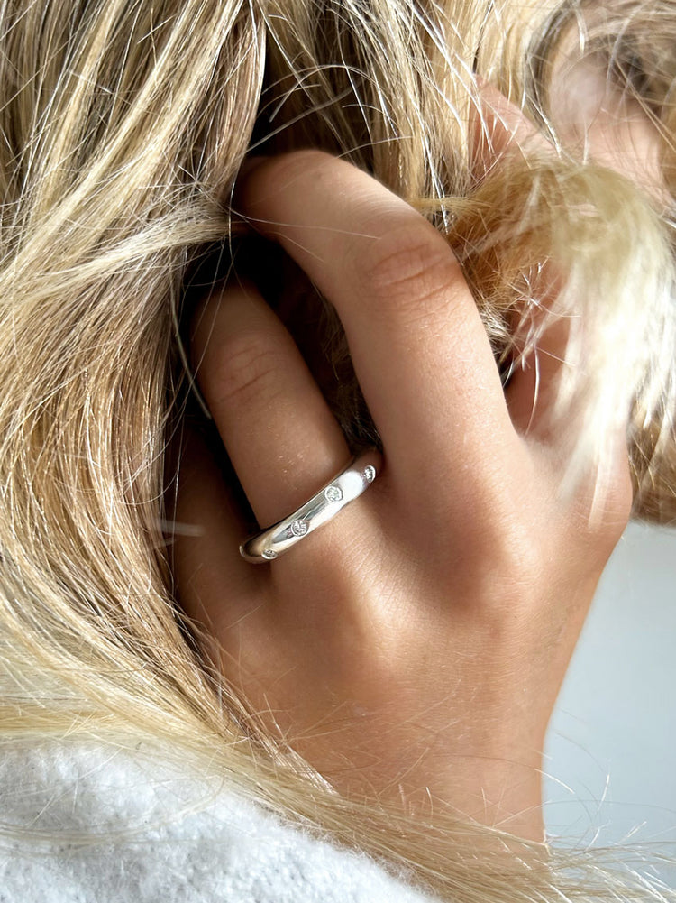 Tjej som bär en diamantring i silver med flera diamanter.