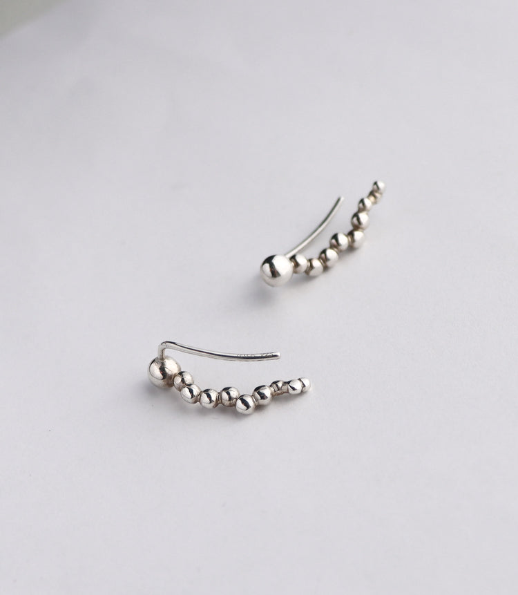 Silverörhängen med kulor och en båge.