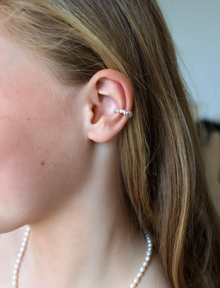 Tjej som bär en ear cuff mitt på örat. Ear cuff i äkta silver med små silverkulor.
