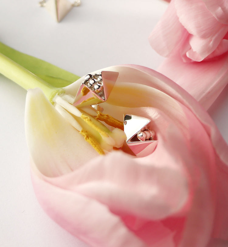Silverörhängen med pyramider som ligger placerade på en tulpan blomma.