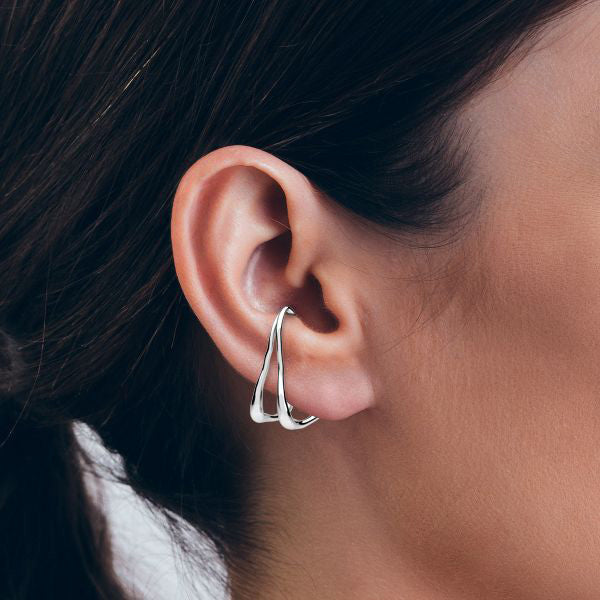 Stor triangelformad ear cuff i silver som hänger på örat.