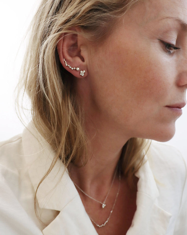 Tjej som bär två örhängen i olika hål och matchande halsband.