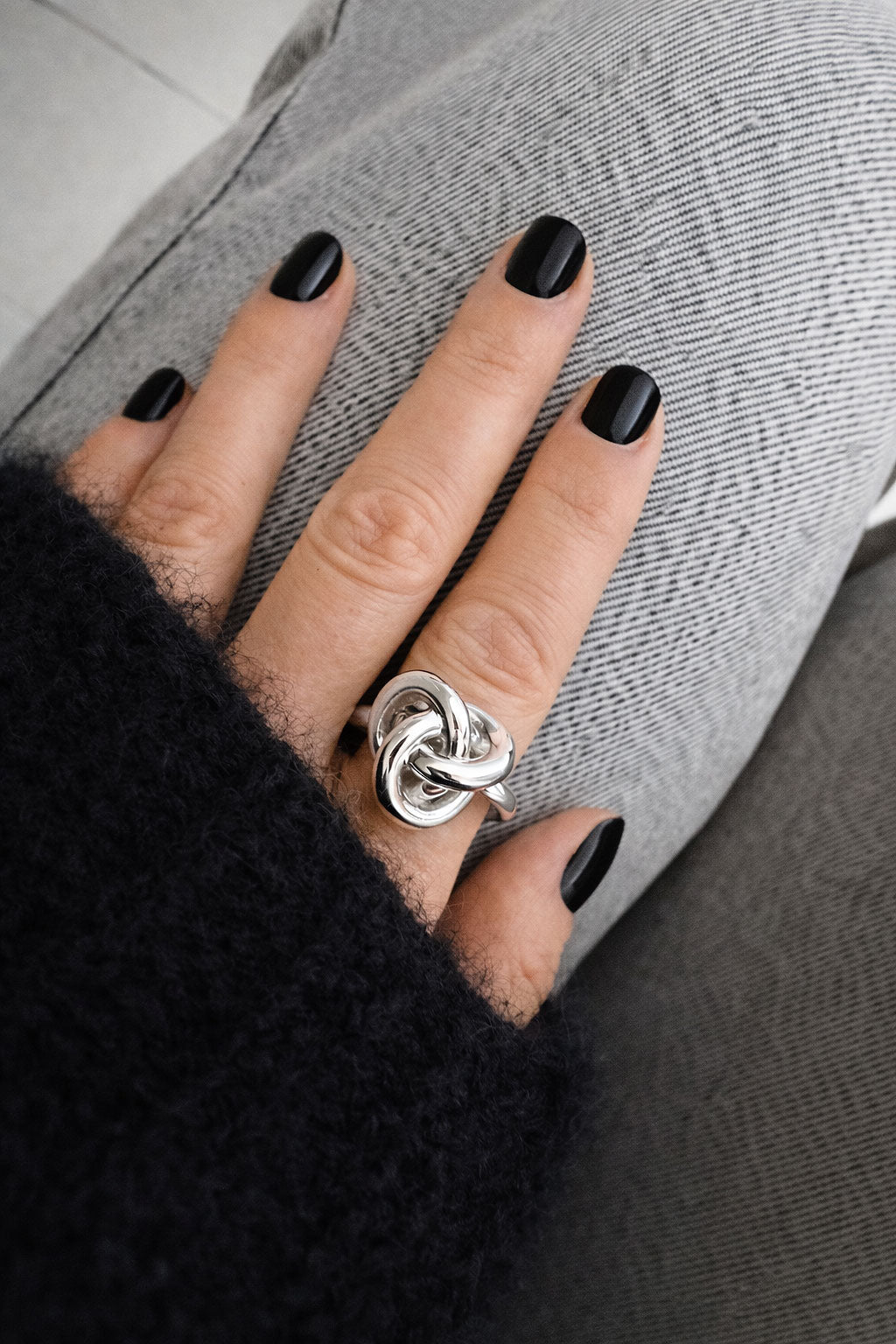Tjej som bÀr en ring i Àkta silver med en stor knut pÄ pekfingret.