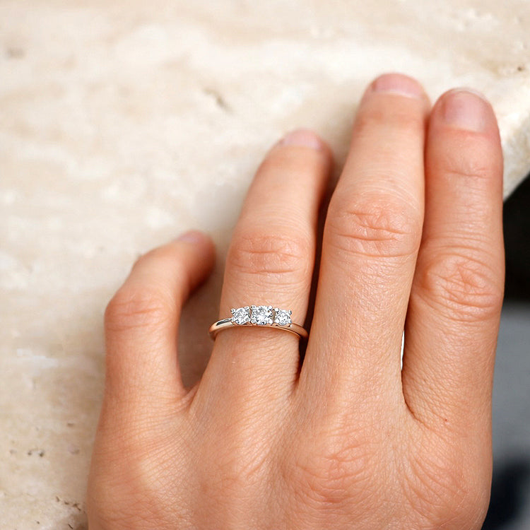 Kvinna som bär förlovningsring med tre diamanter.