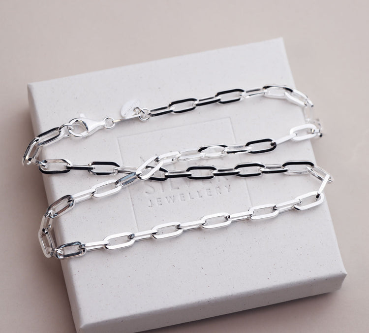 silverkedja som ligger på en vit ask. Kedjan har ovala länkar.