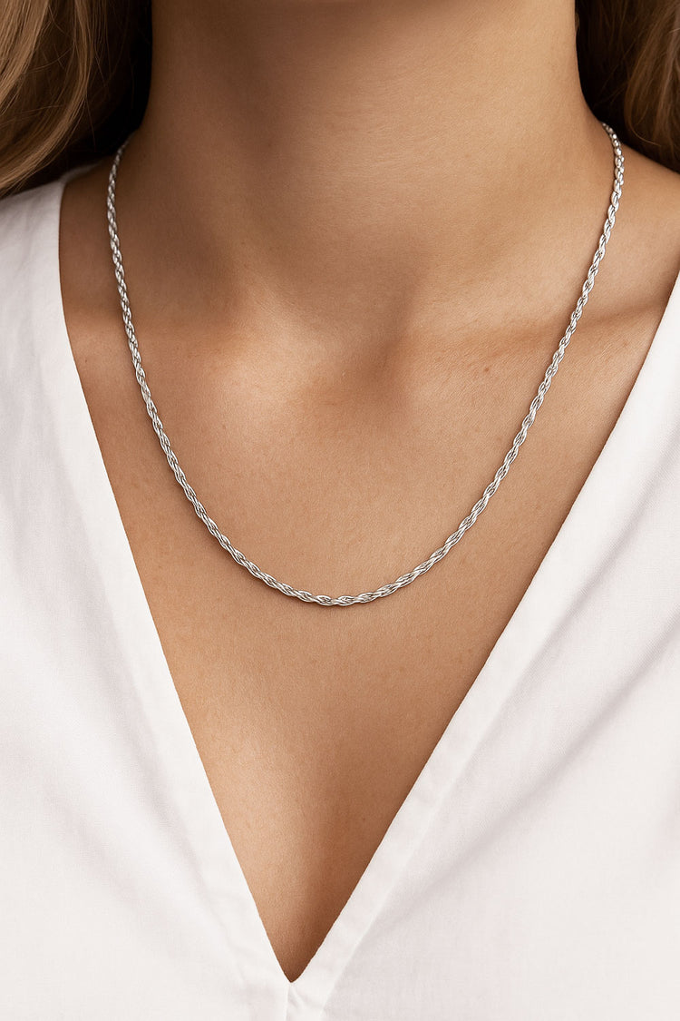 Silverhalsband på en kvinna med Rope kedja, bärs till urringad vit blus.