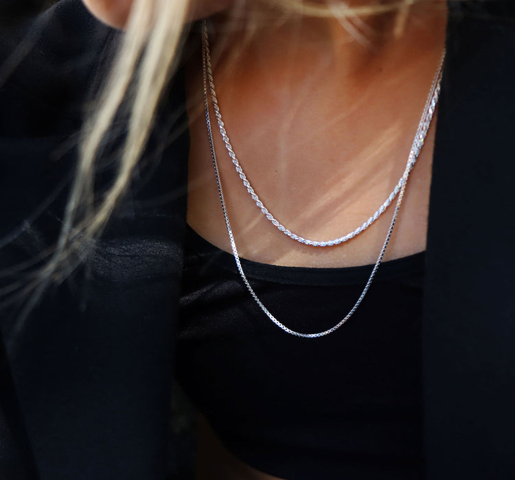 Tjej som bär lager med silverkedjor som halsband