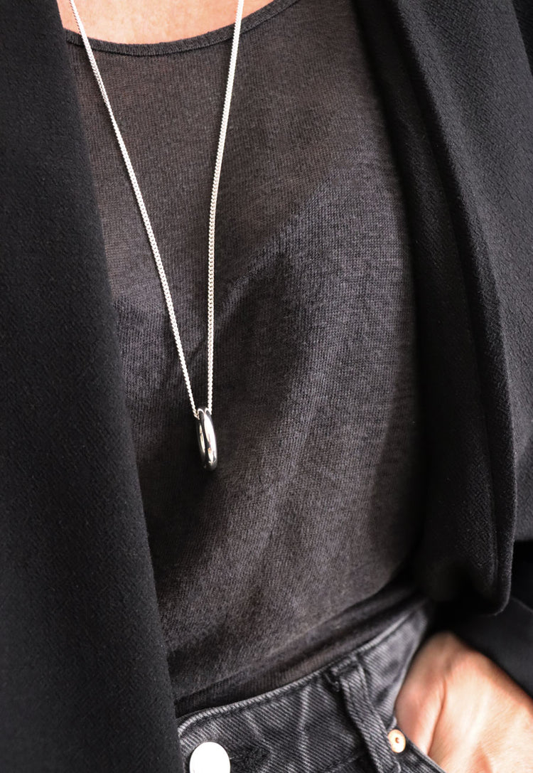 Tjej som bär ett långt halsband med silverring i kedja.