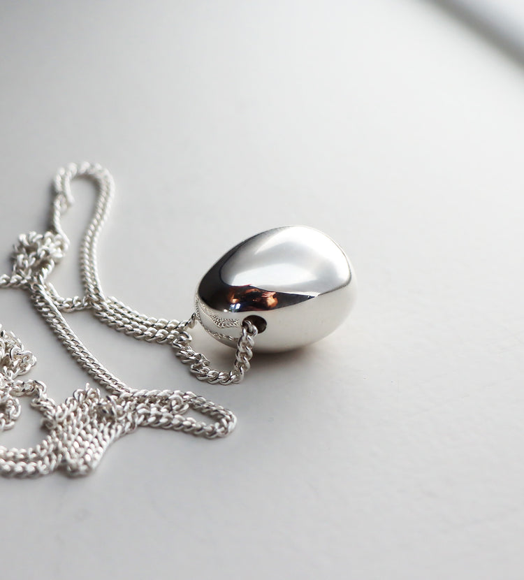 Ett stort silverägg med en kedja som går genom ett hål i ägget.