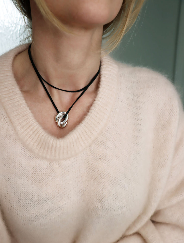 Tjej som bär ett choker halsband med svart läderband och två tjocka länkar.