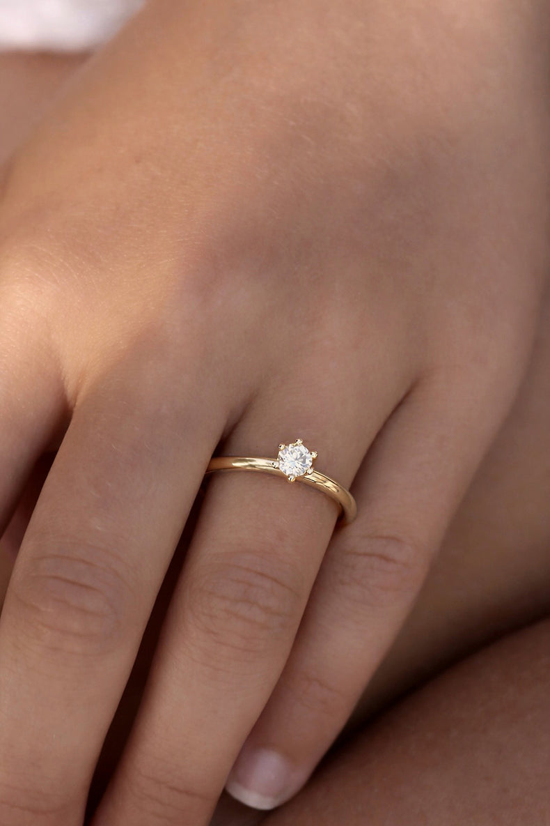 Kvinna som bör en förlovningsring i guld med 0,25 ct diamant. Ring med en sten / solitÀrring.