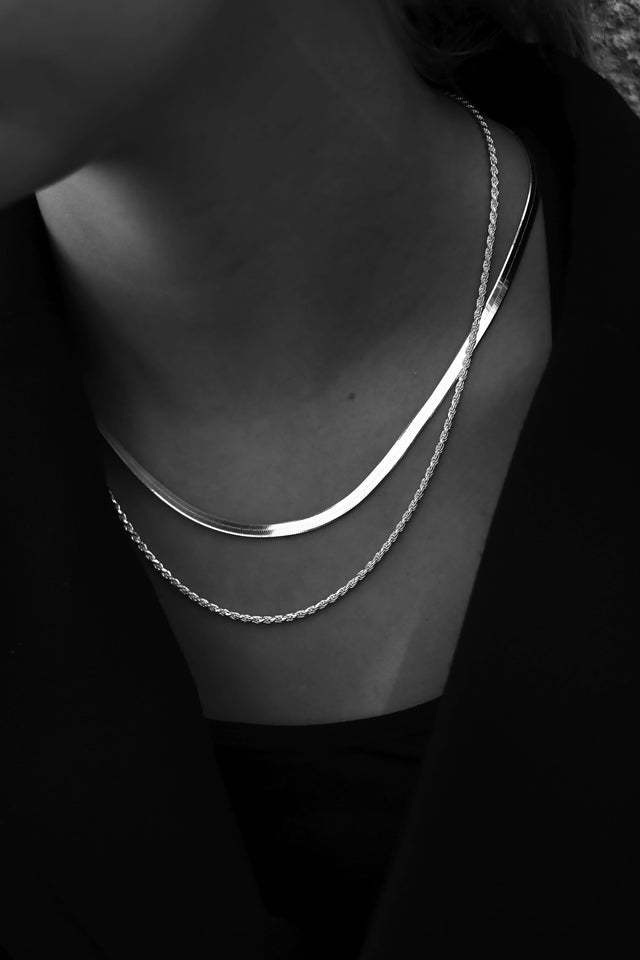 Halsband med silverkedjor i olika längder. En repkedja och en platt ormkedja.