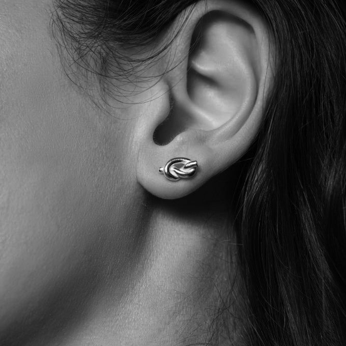 Tjej som bär små örhängen med silver knutar