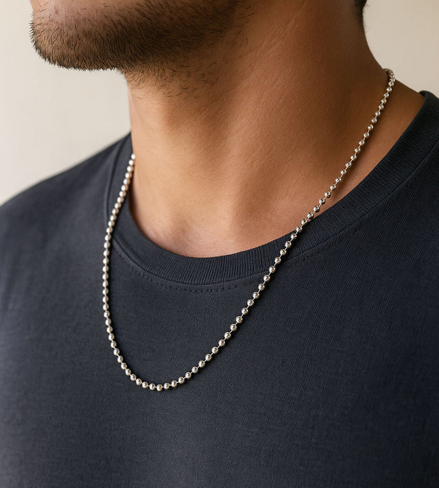 Man som bär en silverkedja av modell kulkedja utanpå en mörkgrå t-shirt. kedjan är 60 cm lång.