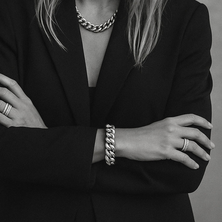 Kvinna som bär ett brett kedjearmband och matchande halsband med kedja i silver.