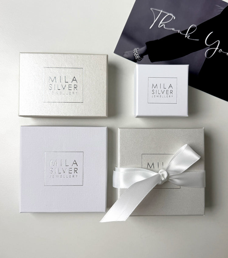 Askar i olika storlekar i vitt och cremevitt med Mila Silvers logotyp
