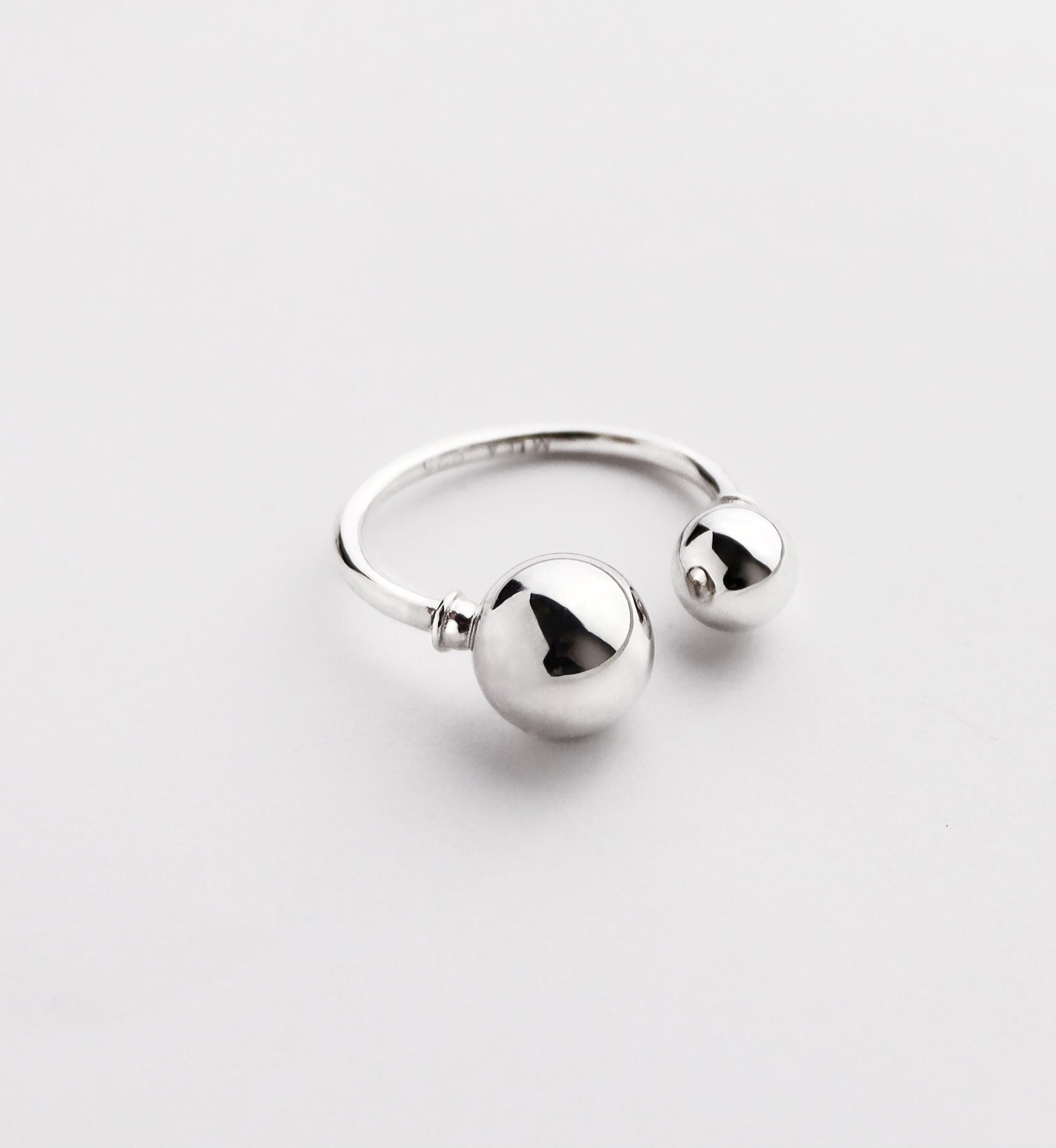 Silverring som är öppen med en stor och en liten silverkula.