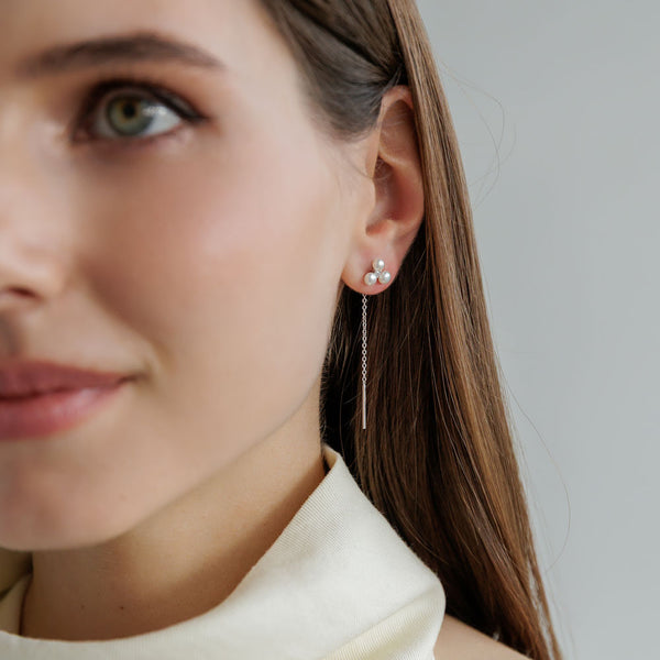 Tjej som bär ett par hängande pärlörhängen i silver.