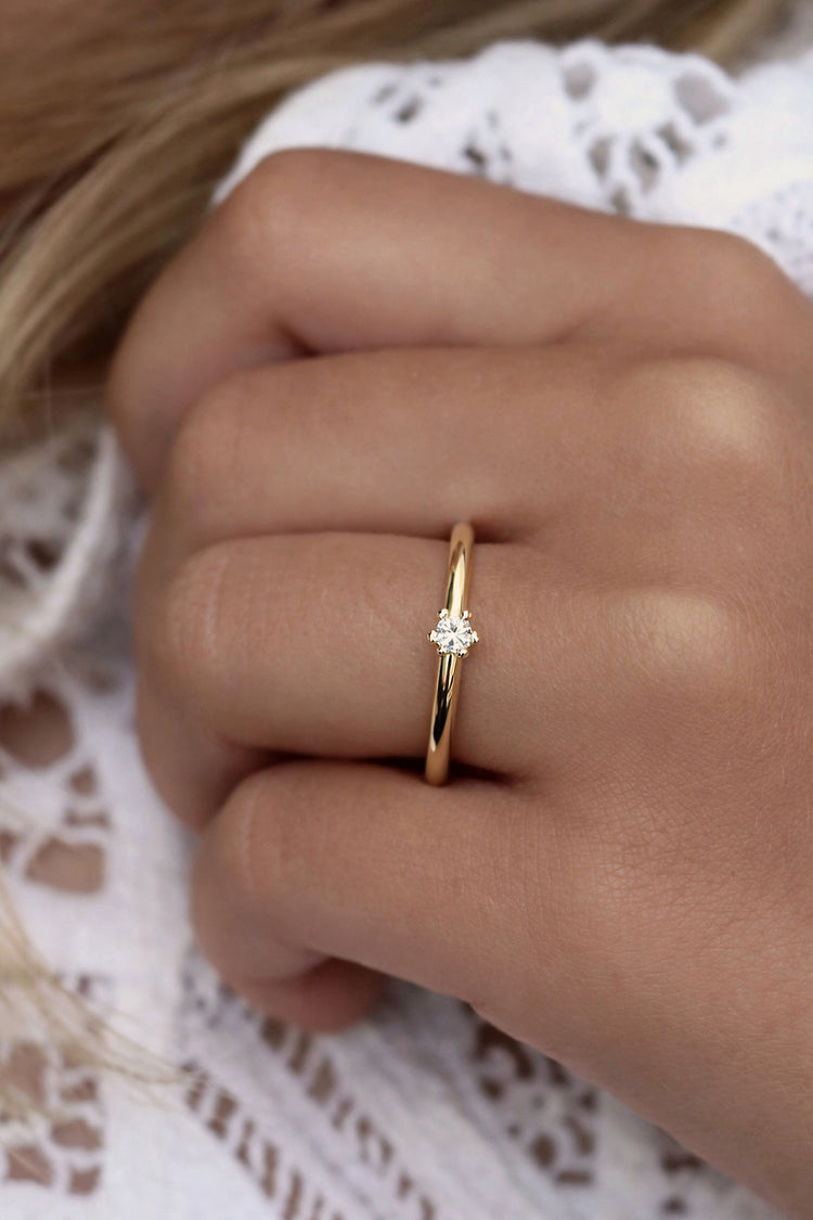Tjej som bär en guldring med 0,10 ct diamant som förlovningsring