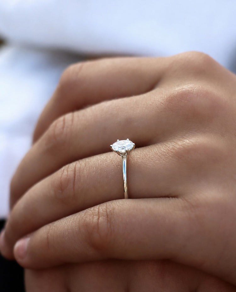 Tjej som bär en förlovningsring i vitguld med oval diamant 0,5 ct.