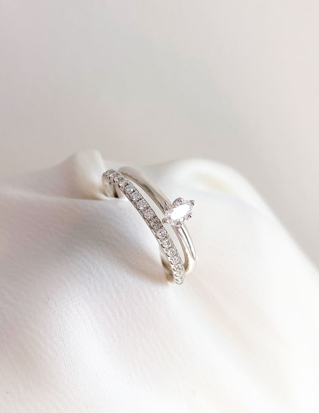 Två diamantringar i kombination. En ring med ett band av diamanter och en ring med ensam oval diamant.