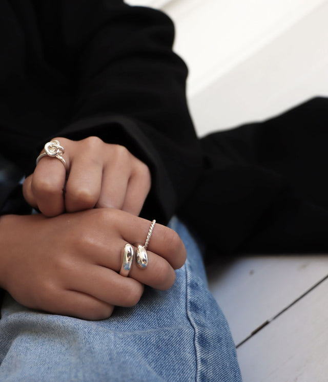 Tjej som bÀr en stor silverring som gÄr omlott pÄ fingret. Hon bÀr fler silverringar pÄ de andra fingrarna.