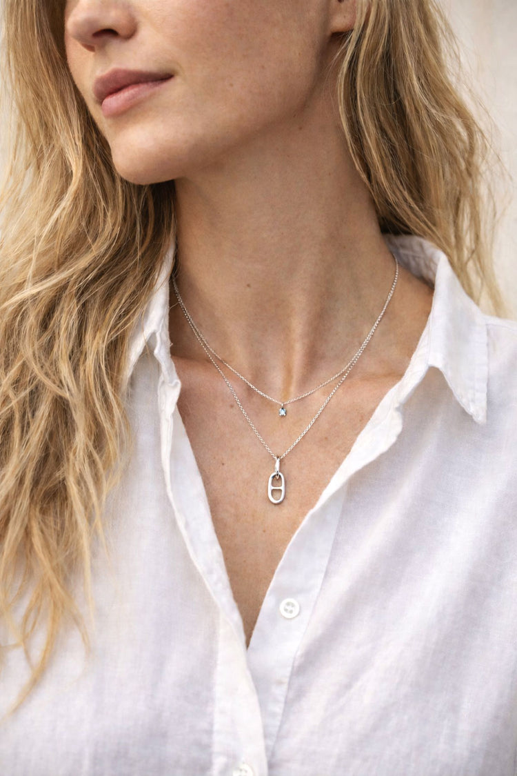 Tjej som bär ett halsband med länkar i tunn kedja kombinerat med ett kortare halsband.