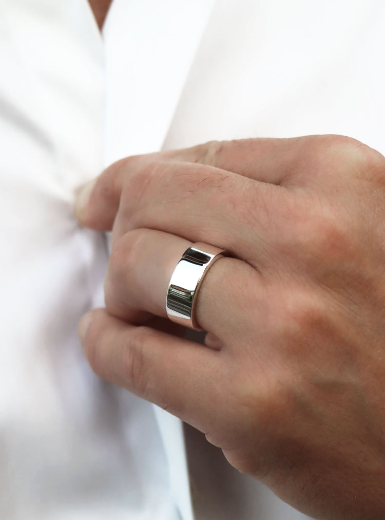 Man som bär en bred silverring med blank slät yta.