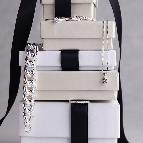 En stapel med present-askar där silversmycken är placerade mellan askarna.