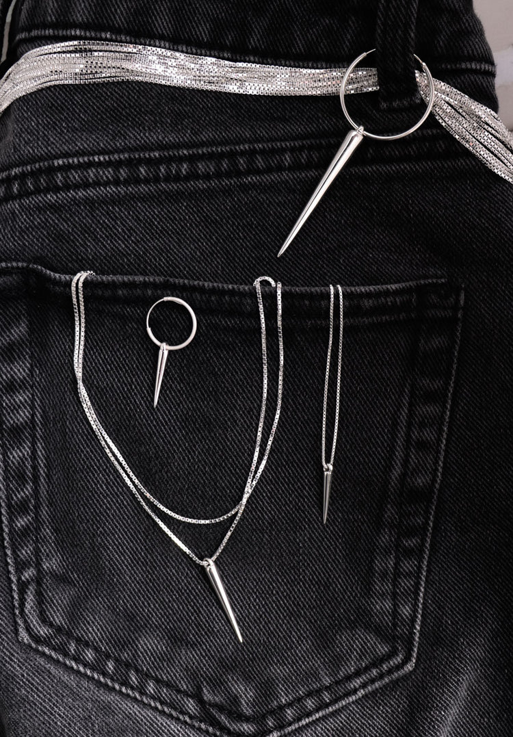 Silversmycken med spetsar och kedjor placerade svart jeanstyg.