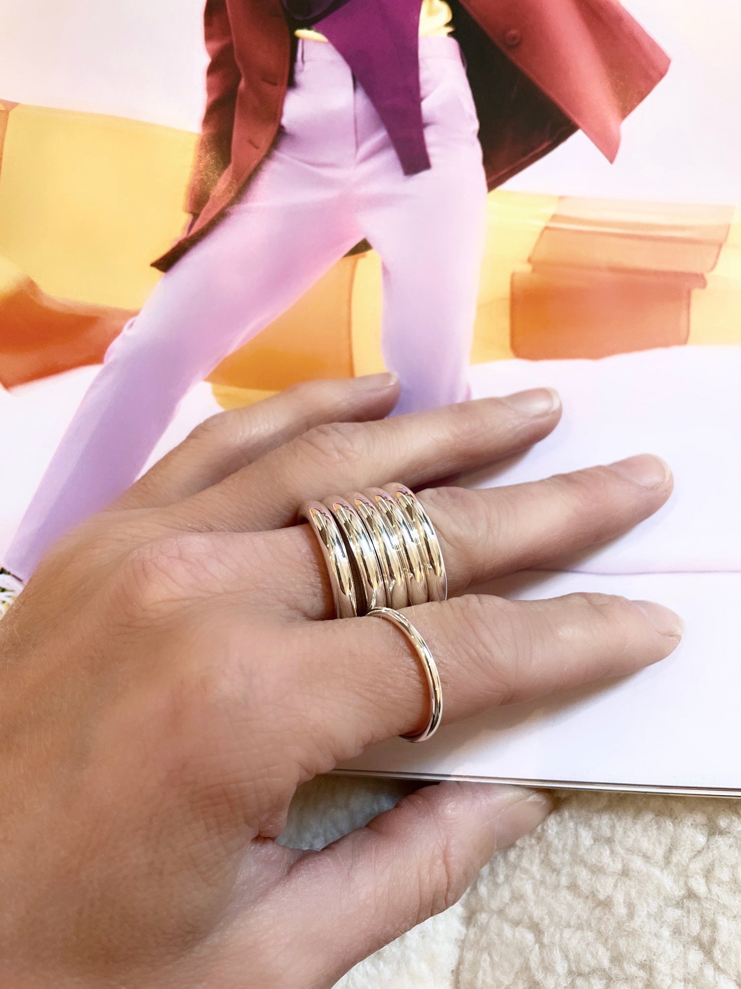 Bred ring stack med fyra tjocka silverringar som bÀrs pÄ samma finger.