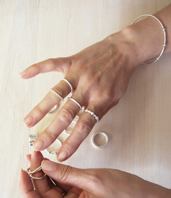 Tjej som provar olika silverringar på olika fingrar