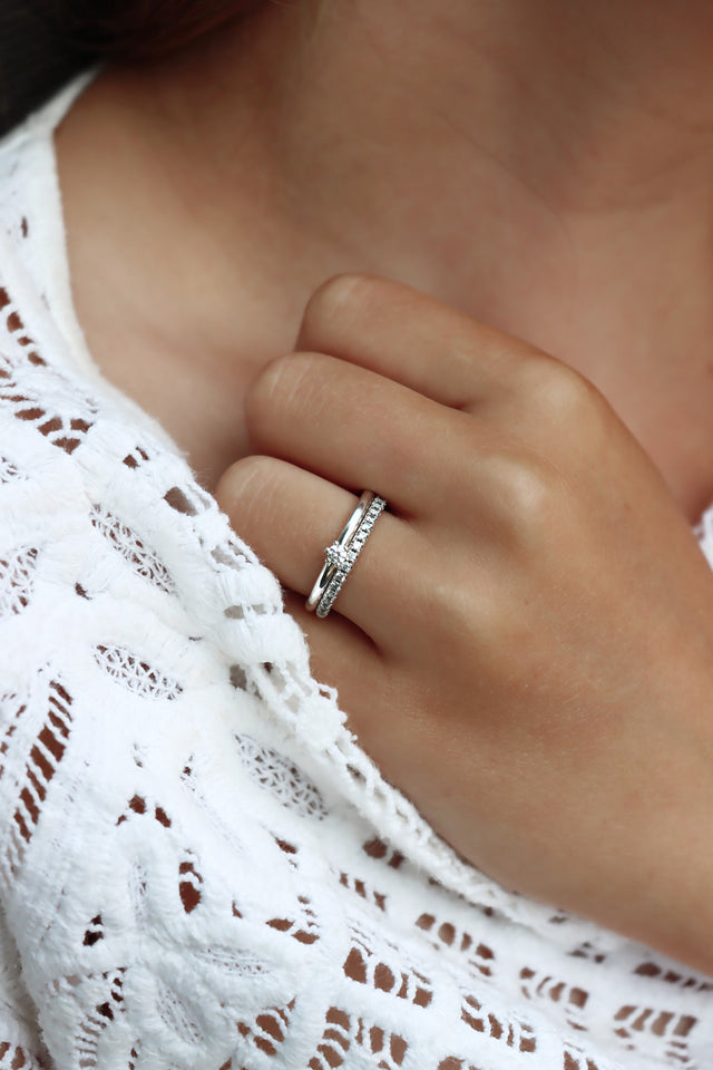 Tjej som bär ett set med vigsel och förlovningsring. Silverringar med diamanter.