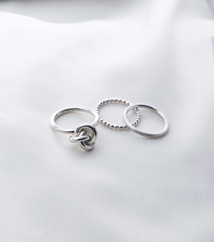 Tre silverringar som ligger på ett tyg.