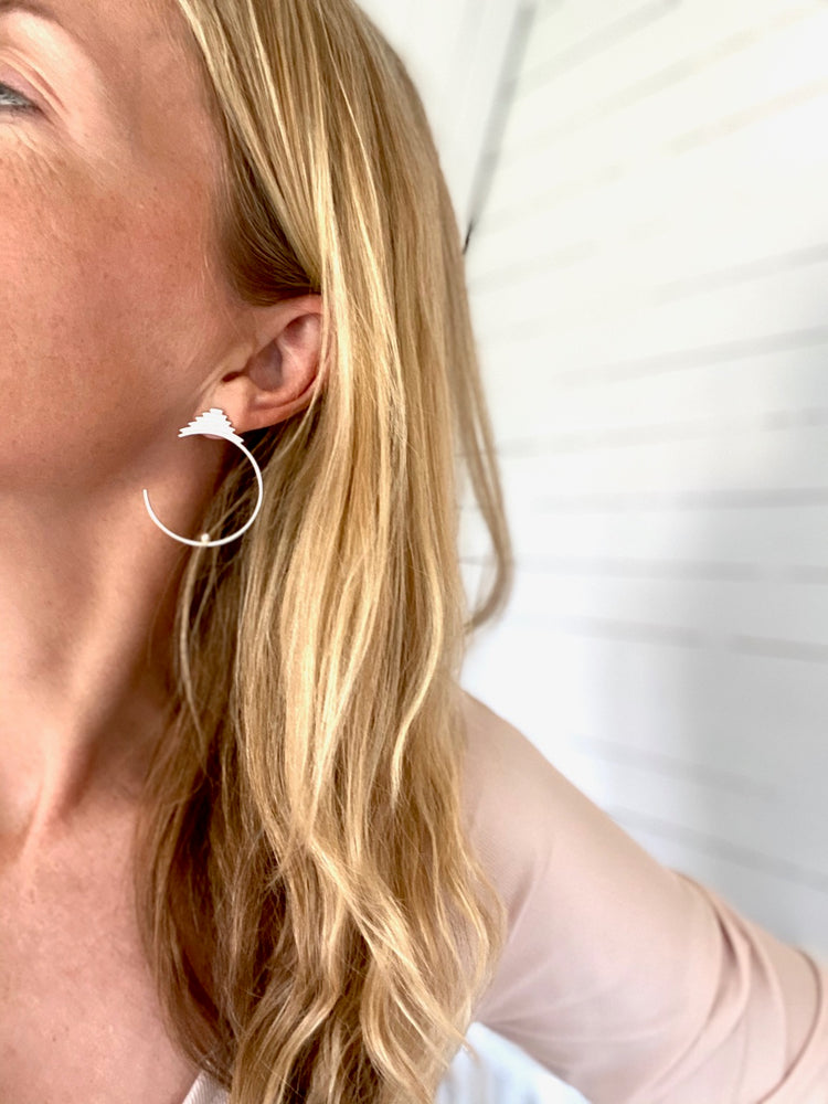 Stora örhängen I silver som sitter fast på örat.