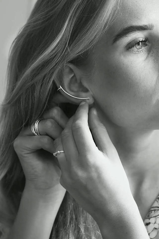 Tjej som tar på sig ett långt silverörhänge som följer örats form.