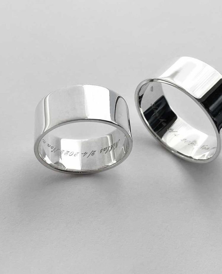Två silverringar som har graverad text på insidan.