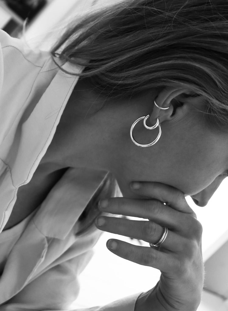 Silver hoop ringar i olika storlekar kombinerade med en ear cuff i silver som bärs på samma öra.