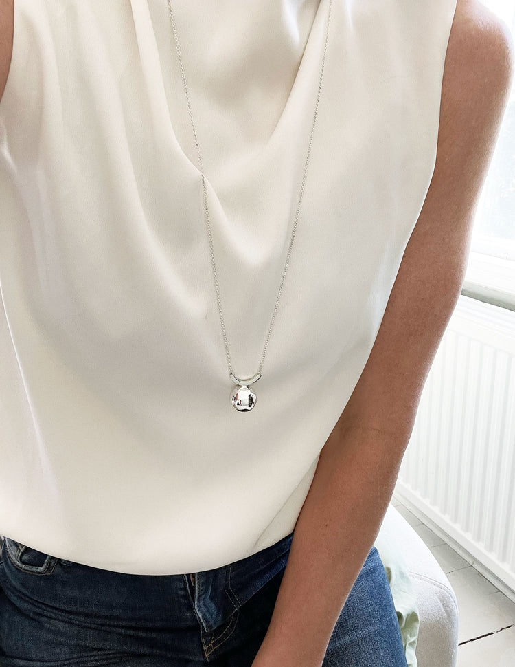 Ett långt silverhalsband med stor silverkula.